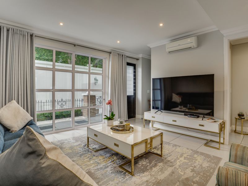 A bright and modern living room featuring tiled floors, recessed lighting, crown molding, and large glass sliding doors leading to an outdoor area.
