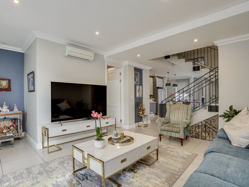 Spacious open-plan living area featuring tiled flooring, recessed lighting, and an elegant wrought iron staircase leading to the upper level.