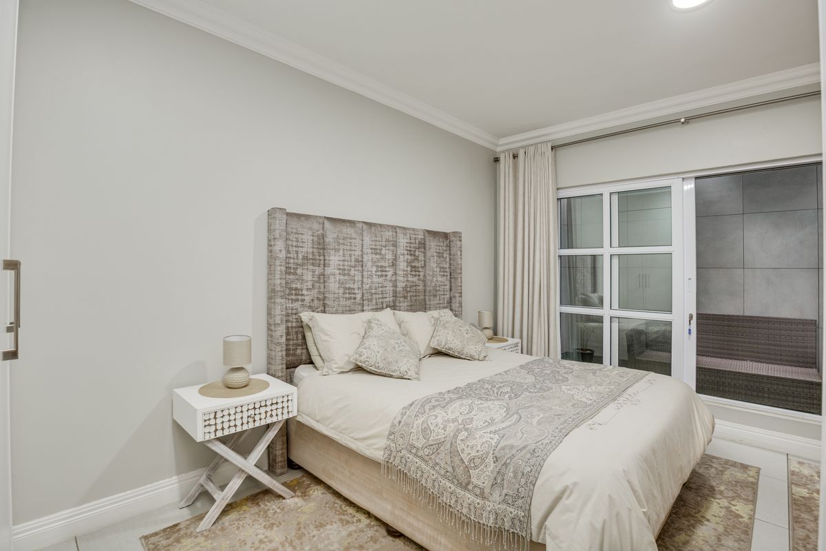 A well-maintained bedroom featuring crown molding, tiled flooring, and a sliding glass door providing access to an outdoor area.