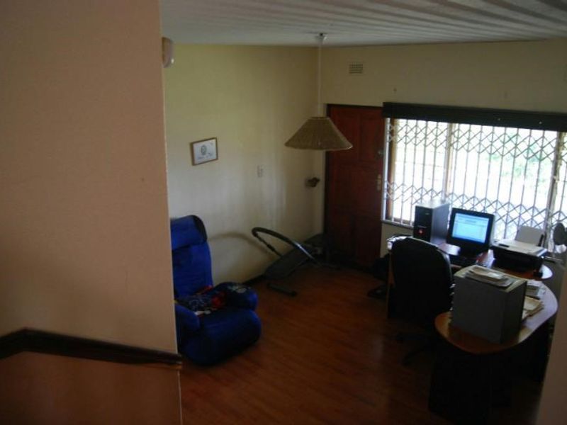 A functional home office space featuring laminate flooring and a window fitted with a security gate, offering a practical area for work or study.