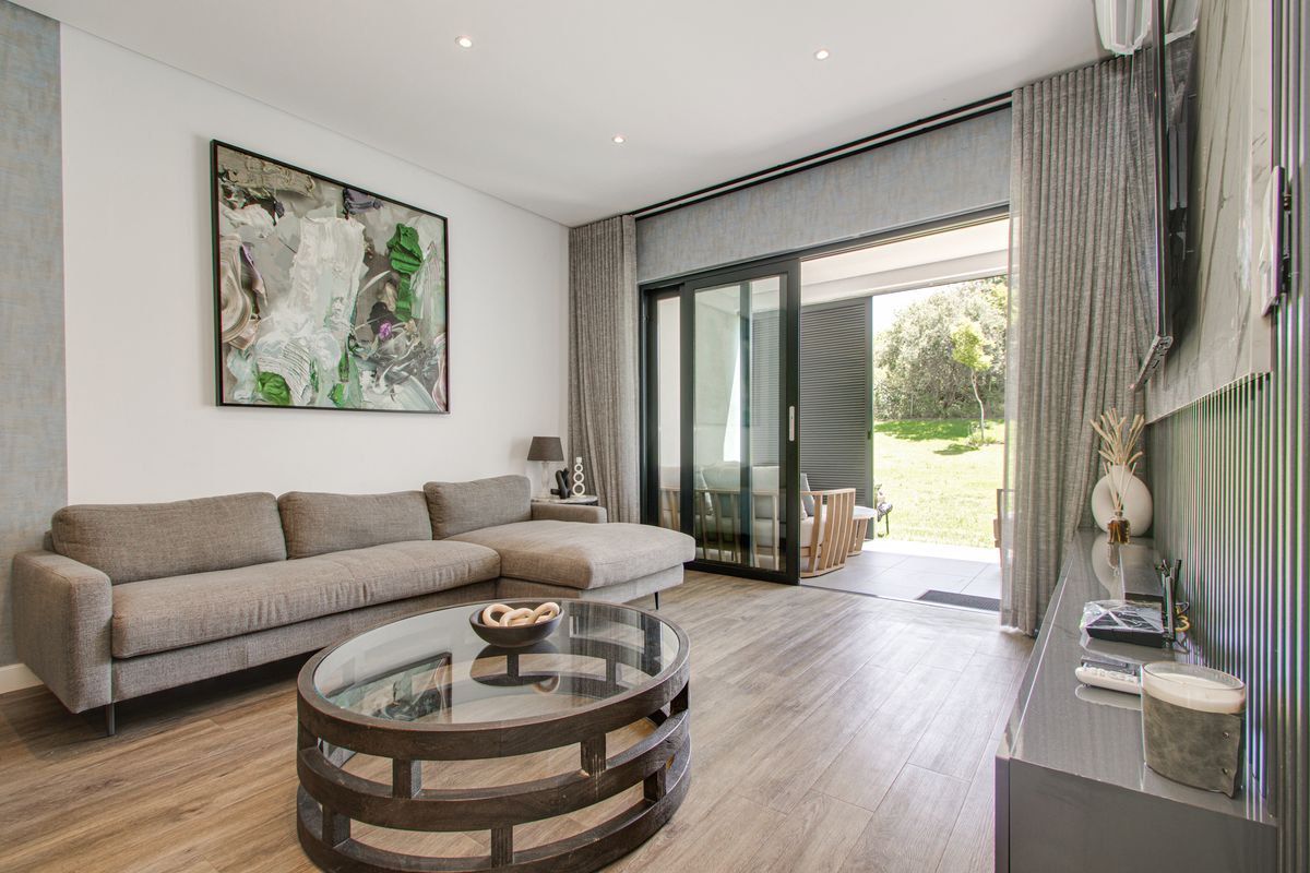 Modern living room featuring laminate flooring, recessed lighting, and large sliding glass doors that open onto a private patio area.