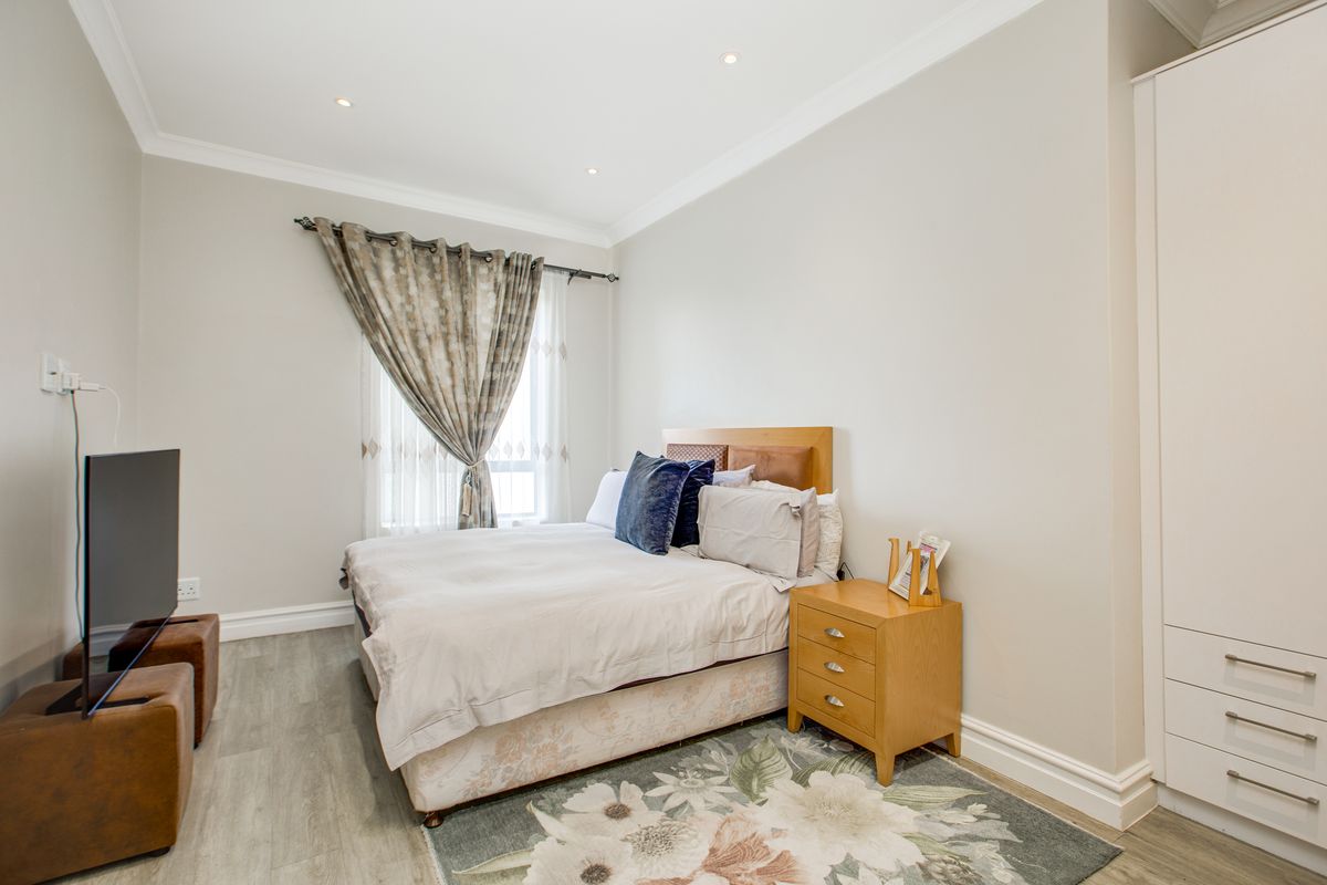 A well-maintained bedroom featuring neutral walls, recessed ceiling lighting, wood-look flooring, and a built-in wardrobe.
