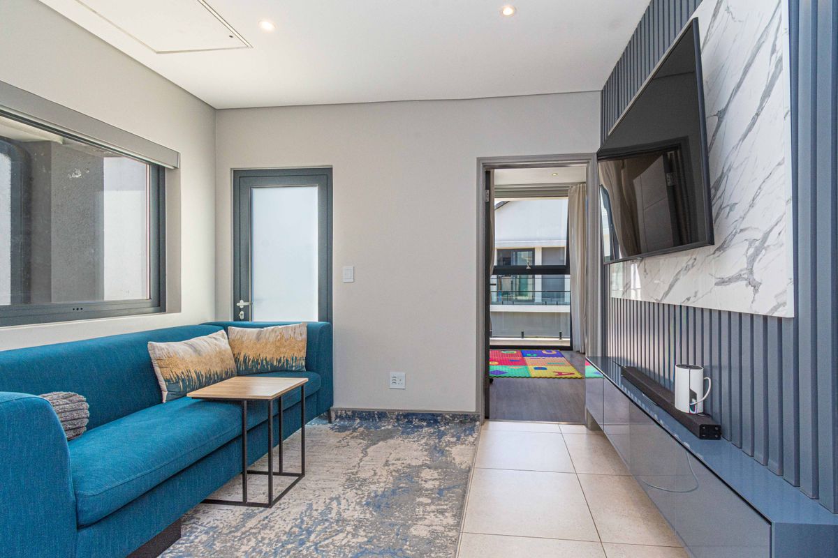 Modern living room featuring a sleek built-in media console with marble-look paneling and vertical slat detailing, complemented by neutral floor tiles.