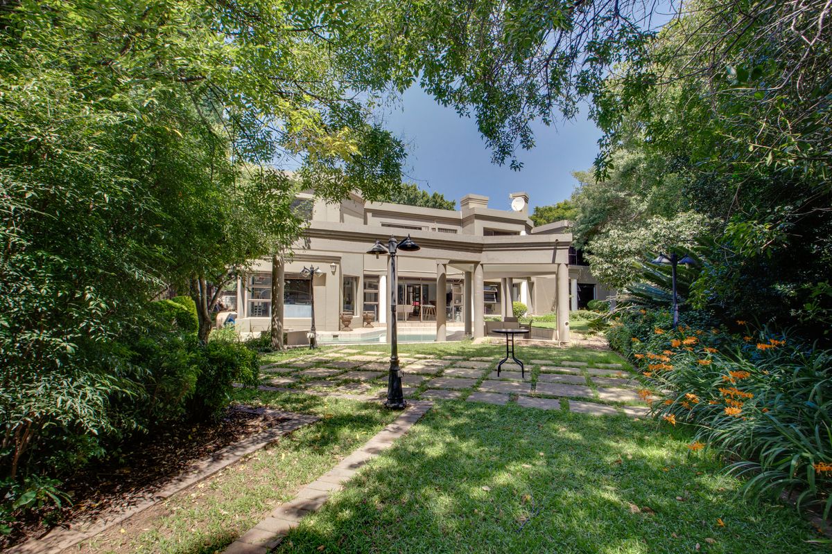 A view of the rear garden featuring a paved patio area, swimming pool, and established landscaping surrounding the property.