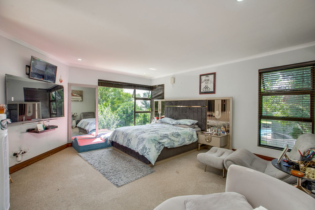 Spacious bedroom featuring large windows with garden views, neutral wall finishes, and integrated lighting.