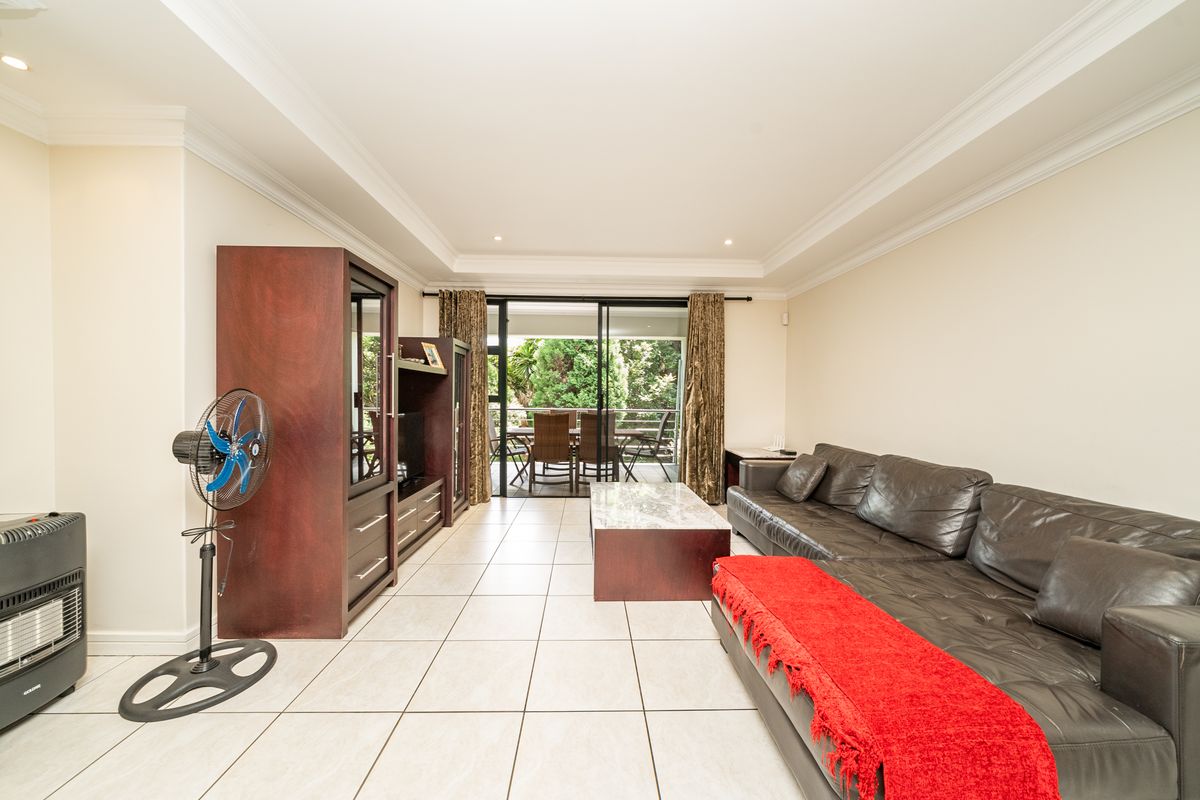 Spacious living room featuring tiled flooring, recessed ceiling lighting, and large sliding glass doors providing direct access to an outdoor patio area.
