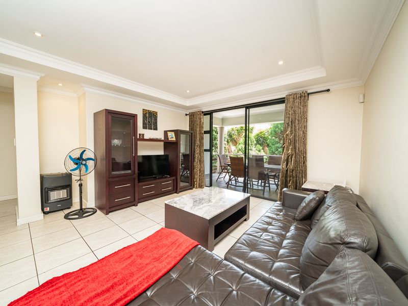 Spacious living room featuring tiled flooring, recessed ceiling lighting, and large sliding glass doors providing seamless access to the outdoor patio area.