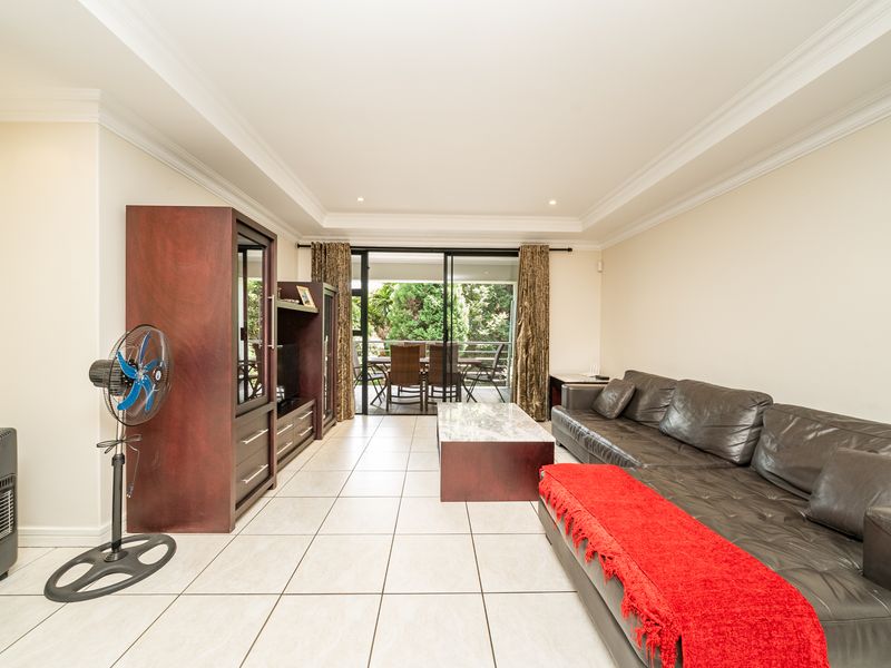 Spacious living room featuring tiled flooring, recessed ceiling lighting, and large sliding glass doors providing direct access to an outdoor patio area.