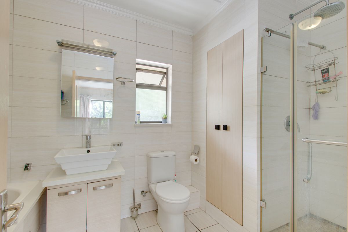 Modern bathroom featuring a vessel sink vanity, glass-enclosed shower, bathtub, and neutral wall tiling.