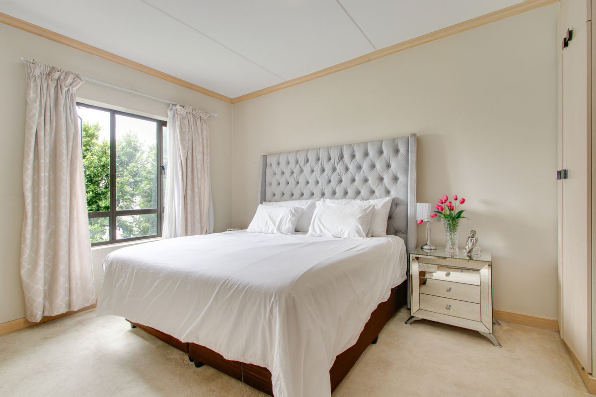 A well-lit bedroom featuring neutral walls, built-in cabinetry, and a large window providing natural light.