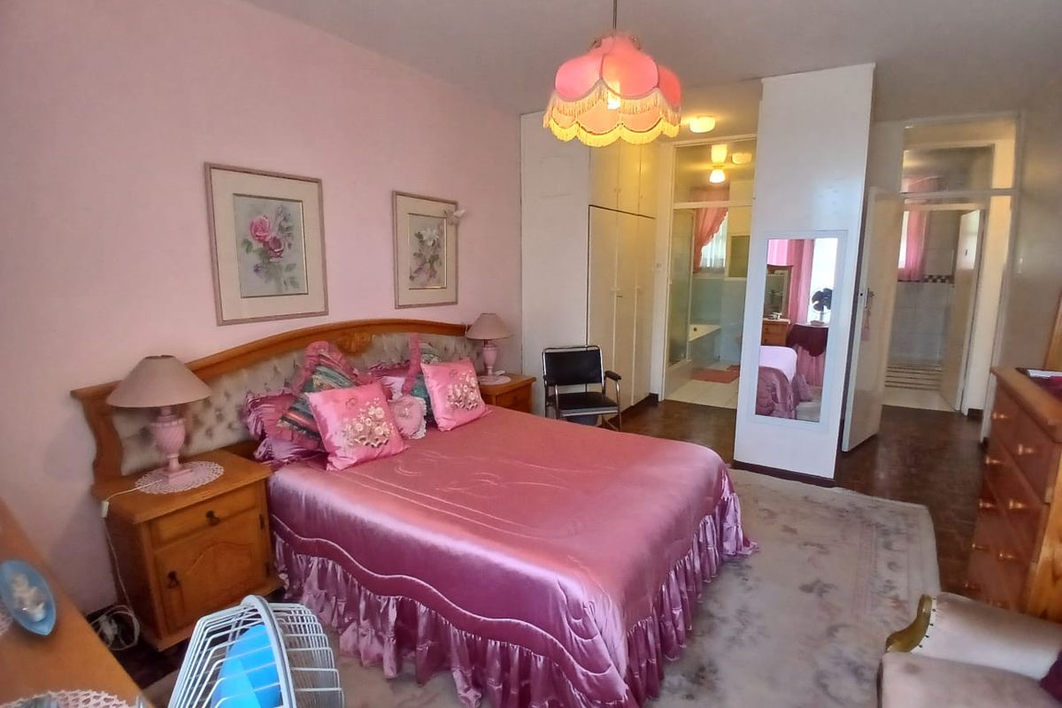 A spacious bedroom featuring built-in cupboards and an en-suite bathroom, offering a functional layout with classic finishes.