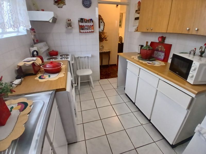 A functional kitchen featuring white cabinetry, laminate countertops, tiled flooring, and a built-in stove with an extractor fan.