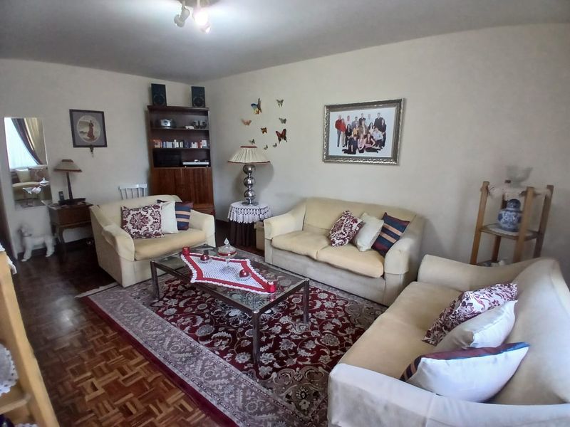 A living room featuring parquet flooring and a central ceiling light fixture, providing a comfortable and traditional living space.