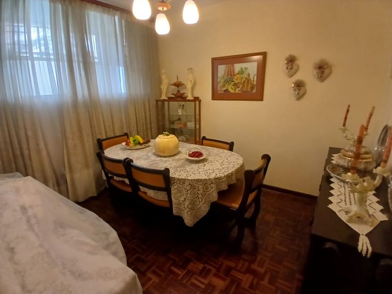 A dining room featuring traditional parquet flooring and a central light fixture, providing a functional space for meals.