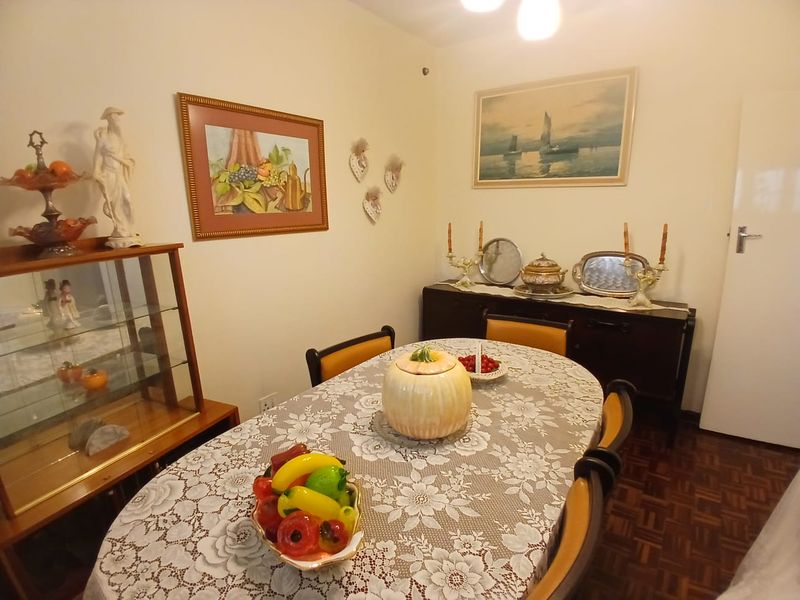A traditional dining room featuring classic parquet flooring and neutral wall finishes, providing a warm and inviting space for formal meals.