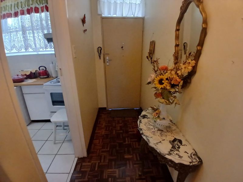 Entrance hallway featuring parquet flooring, leading directly into a functional kitchen area with tiled floors.