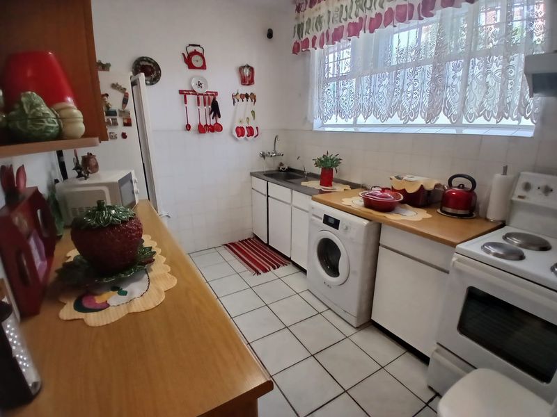 A functional kitchen featuring white cabinetry, tiled flooring, a built-in stove, and an integrated laundry appliance space.