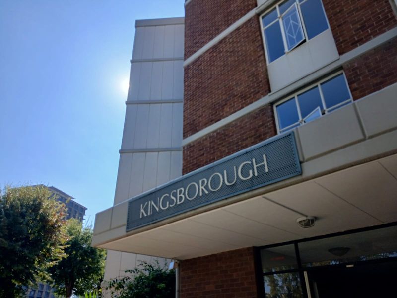 Exterior view of the Kingsborough apartment building entrance, featuring brick facade, signage, and metal window frames.