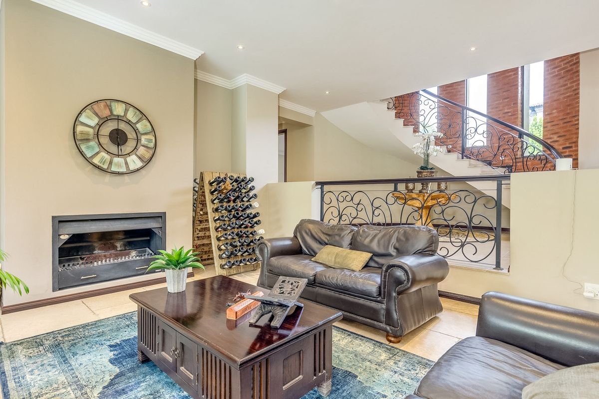 Spacious living room featuring a built-in fireplace, tiled flooring, and an elegant staircase with decorative wrought iron railings.
