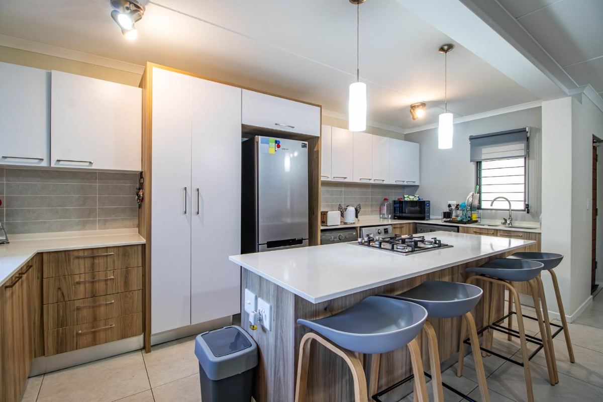 Modern open-plan kitchen featuring a central island with a built-in gas hob, sleek cabinetry, and stone countertops.