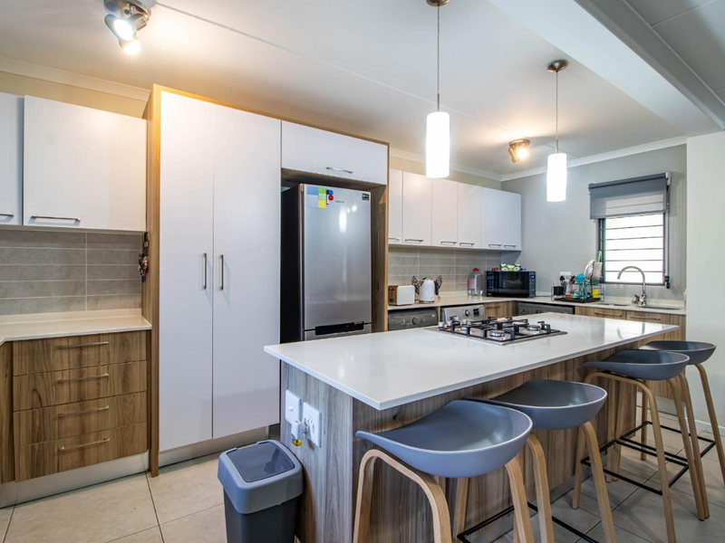 Modern open-plan kitchen featuring a central island with a built-in gas hob, sleek cabinetry, and stone countertops.