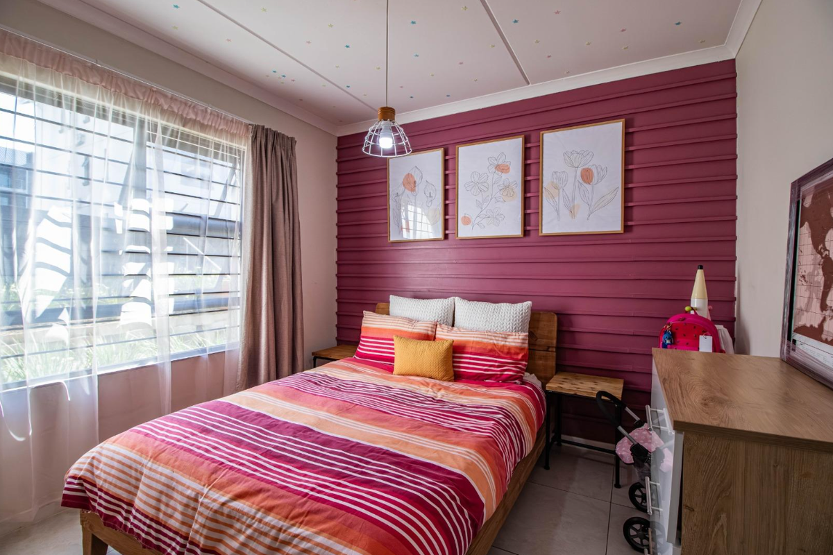 A bedroom featuring a distinctive horizontal timber-slat accent wall, tiled flooring, and large window with security bars.