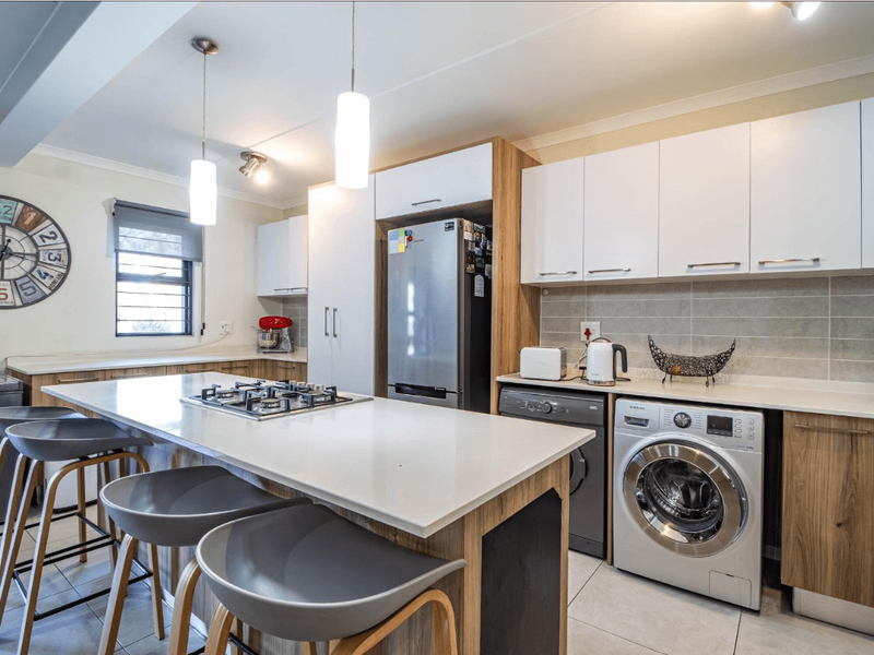 Modern open-plan kitchen featuring a central island with a built-in gas hob, stone countertops, and integrated cabinetry with a sleek, contemporary finish.