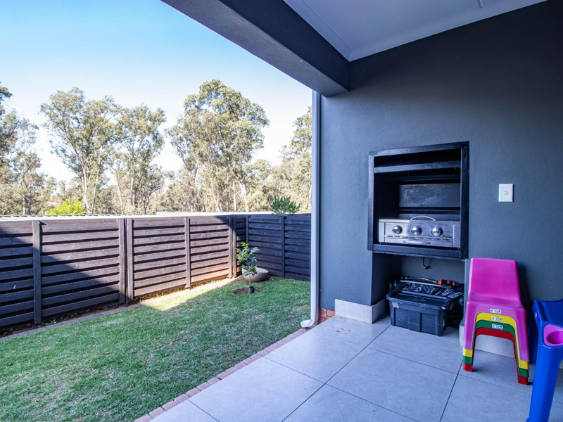 Covered patio area featuring a built-in braai, tiled flooring, and direct access to a private fenced garden.