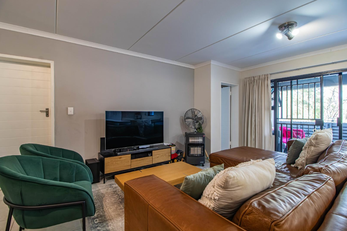 A comfortable living room featuring tiled flooring, neutral wall tones, and sliding glass doors that provide access to an outdoor balcony area.