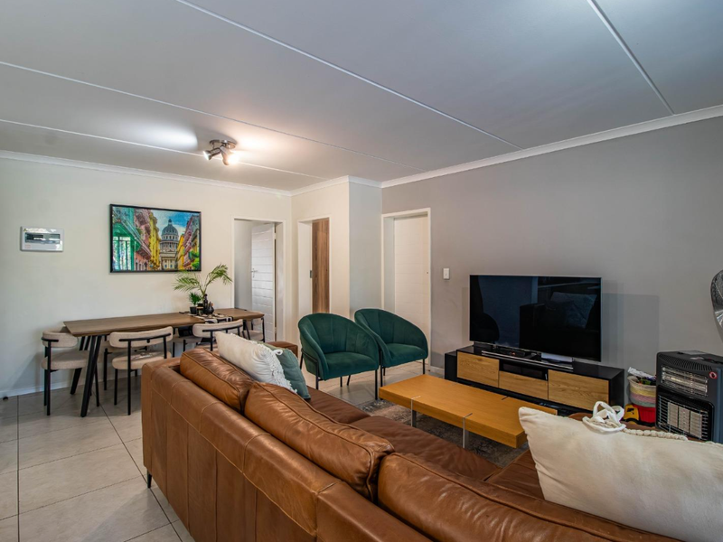 Open-plan living and dining area featuring tiled flooring, neutral wall finishes, and direct access to adjacent rooms.