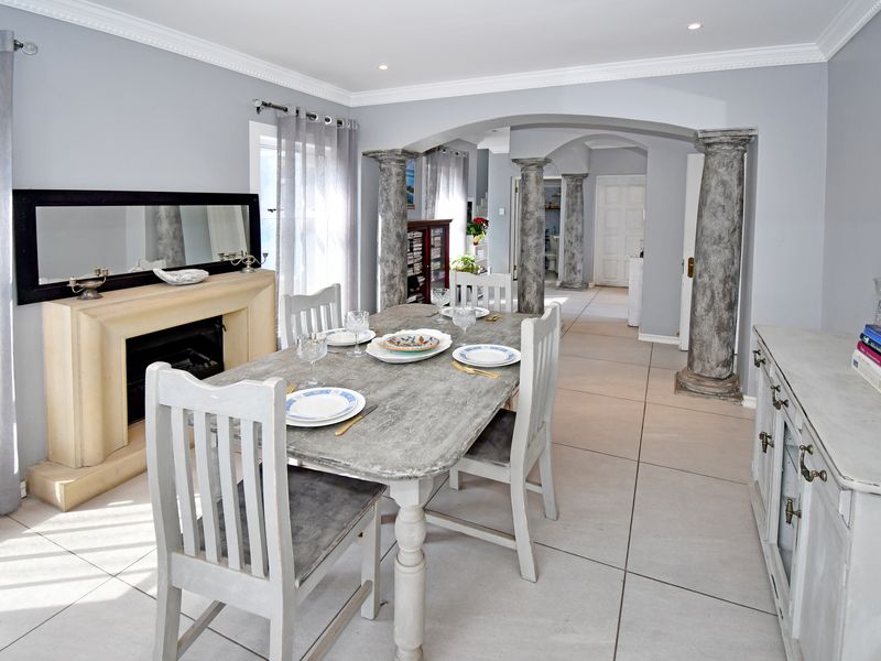 Dining room featuring decorative stone-look columns, tiled flooring, and a built-in fireplace, creating an open-plan flow into the adjacent hallway.