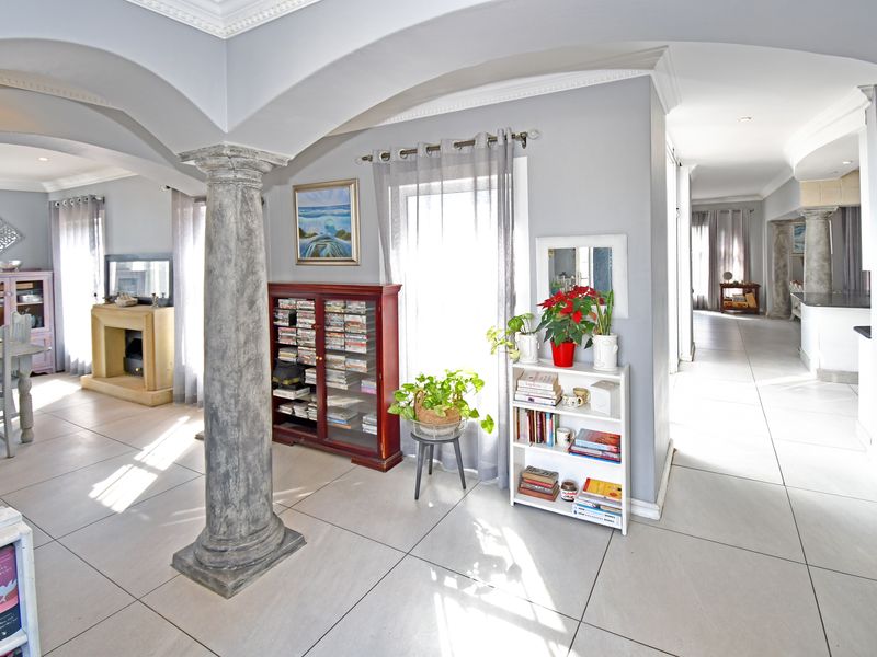 Open plan living area featuring decorative architectural columns, tiled flooring, and arched ceiling details, creating a spacious and connected interior layout.