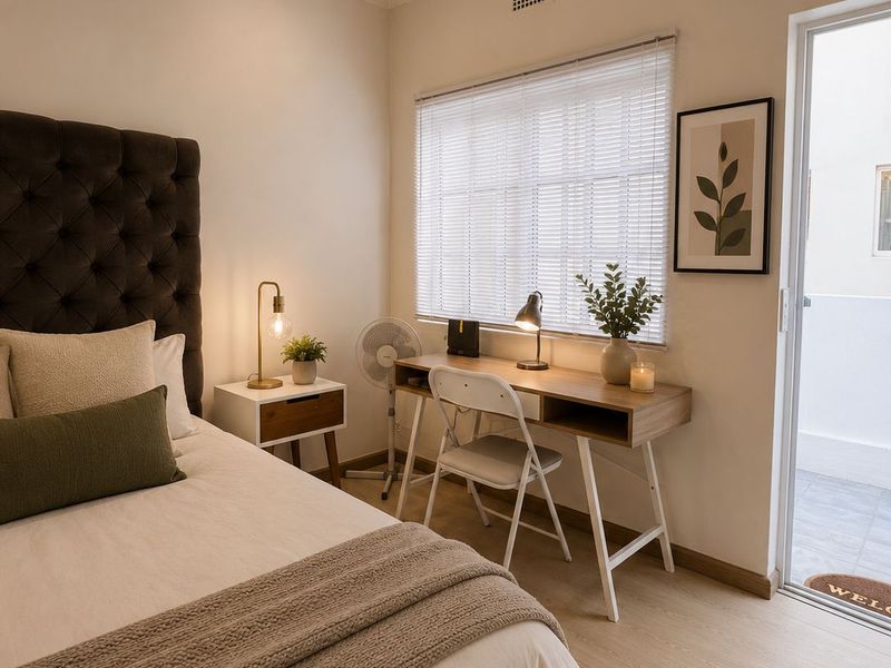 A well-maintained bedroom featuring light laminate flooring, venetian blinds, and a glass sliding door providing access to an outdoor area.