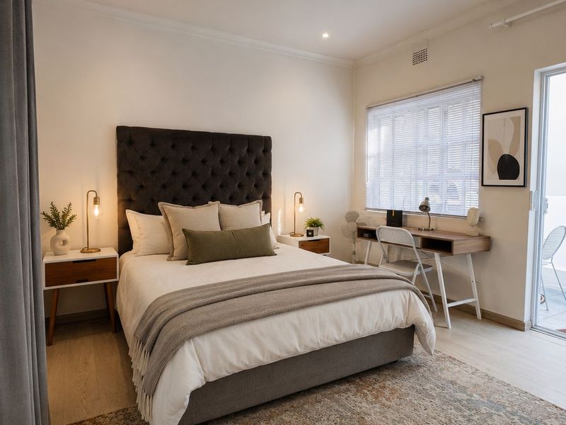 A well-presented bedroom featuring neutral finishes, recessed lighting, laminate flooring, and direct access to an outdoor area via a sliding glass door.