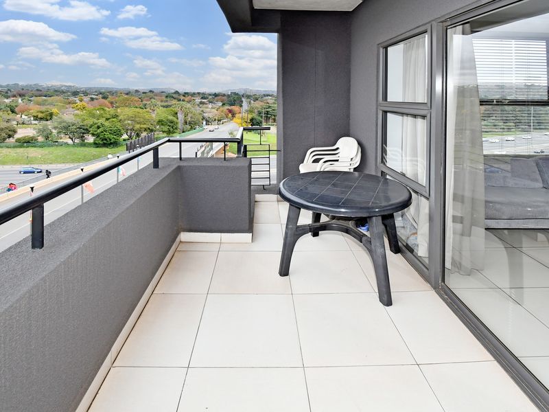A private balcony featuring tiled flooring, a metal railing, and expansive views of the surrounding area.