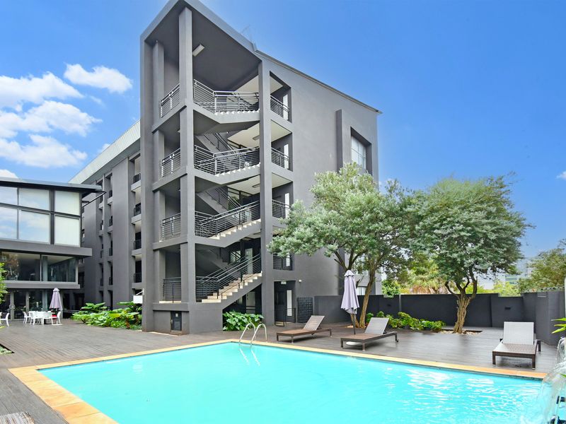 Modern apartment complex exterior featuring a swimming pool, timber decking, and external stairwell access.