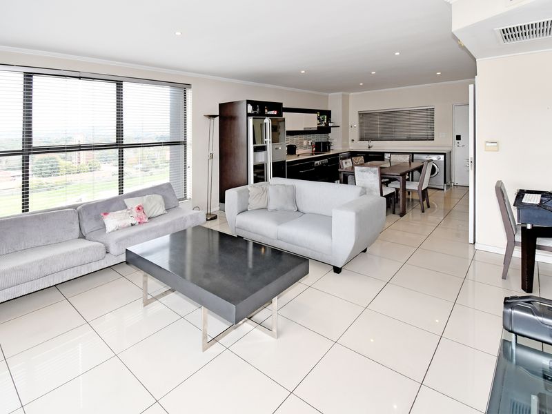 Open-plan living area featuring large windows, tiled flooring, and a modern kitchen with integrated cabinetry and built-in appliances.