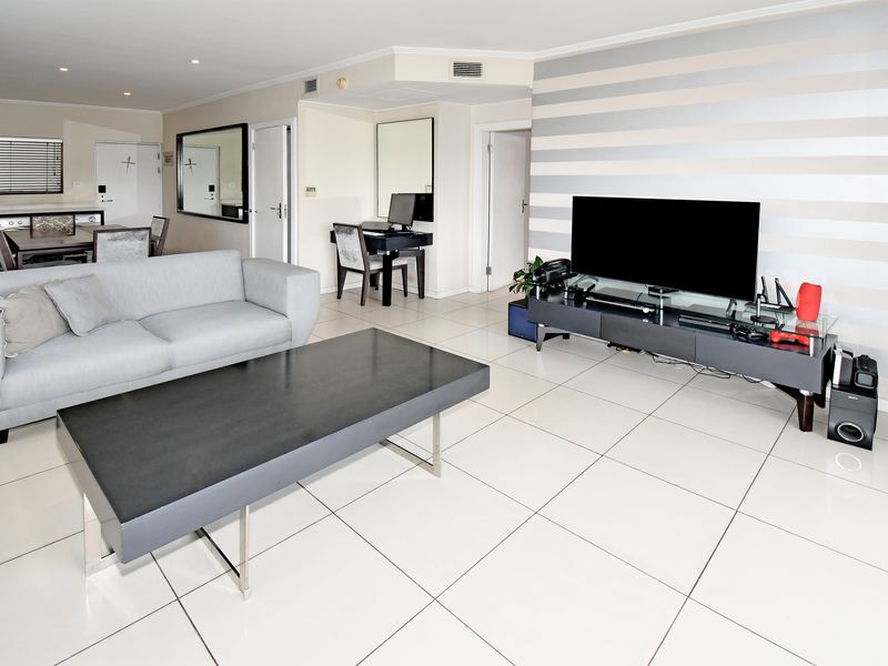 Spacious open-plan living area featuring large format floor tiles, recessed downlighting, and integrated air conditioning vents.