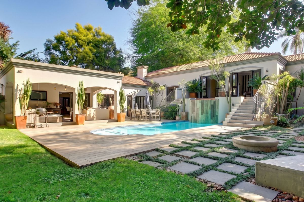 Spacious rear garden featuring a swimming pool, wooden decking, paved pathways, and a covered patio area, ideal for outdoor entertaining.