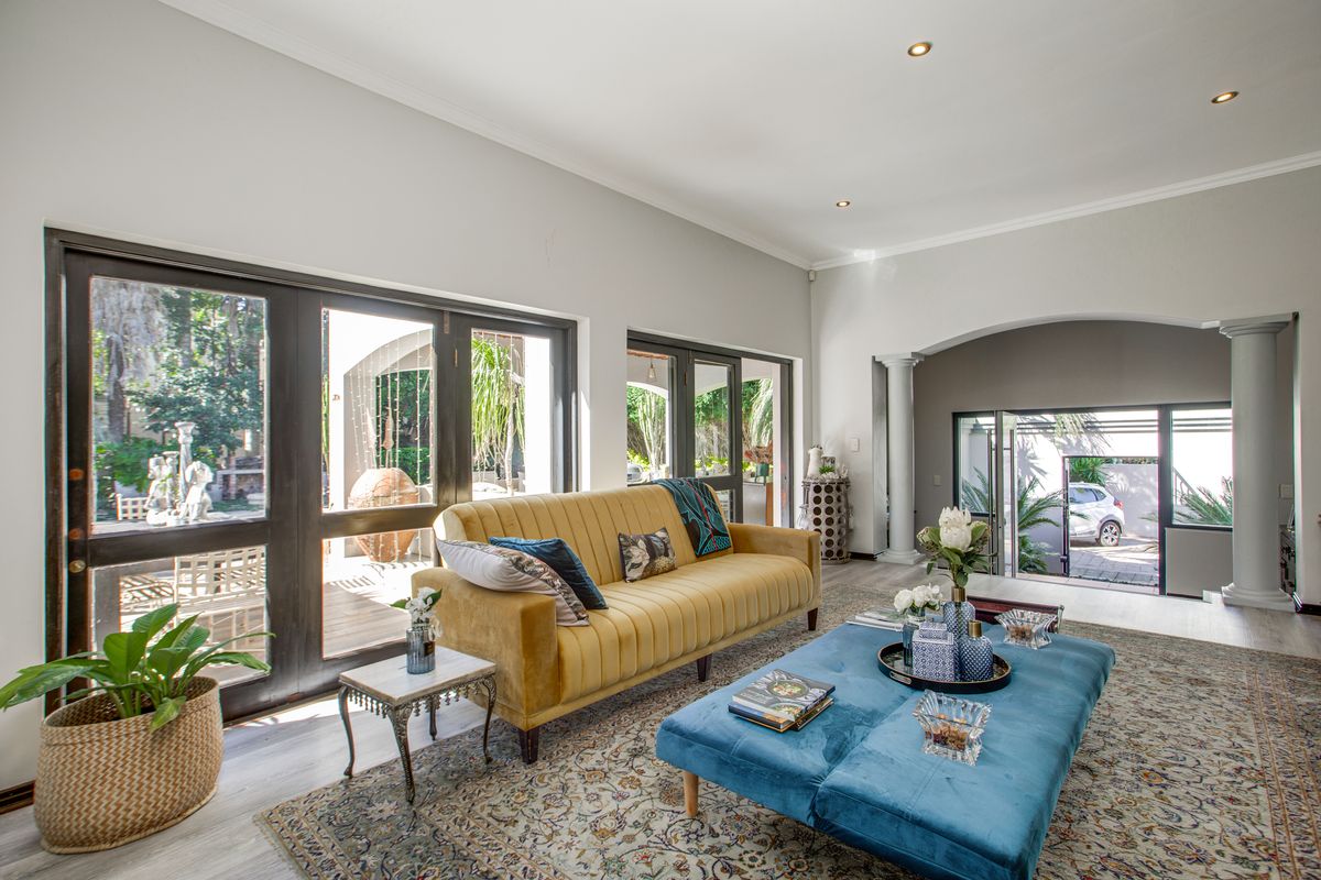Spacious living room featuring large glass sliding doors that open onto a patio, recessed ceiling lighting, and elegant architectural columns.