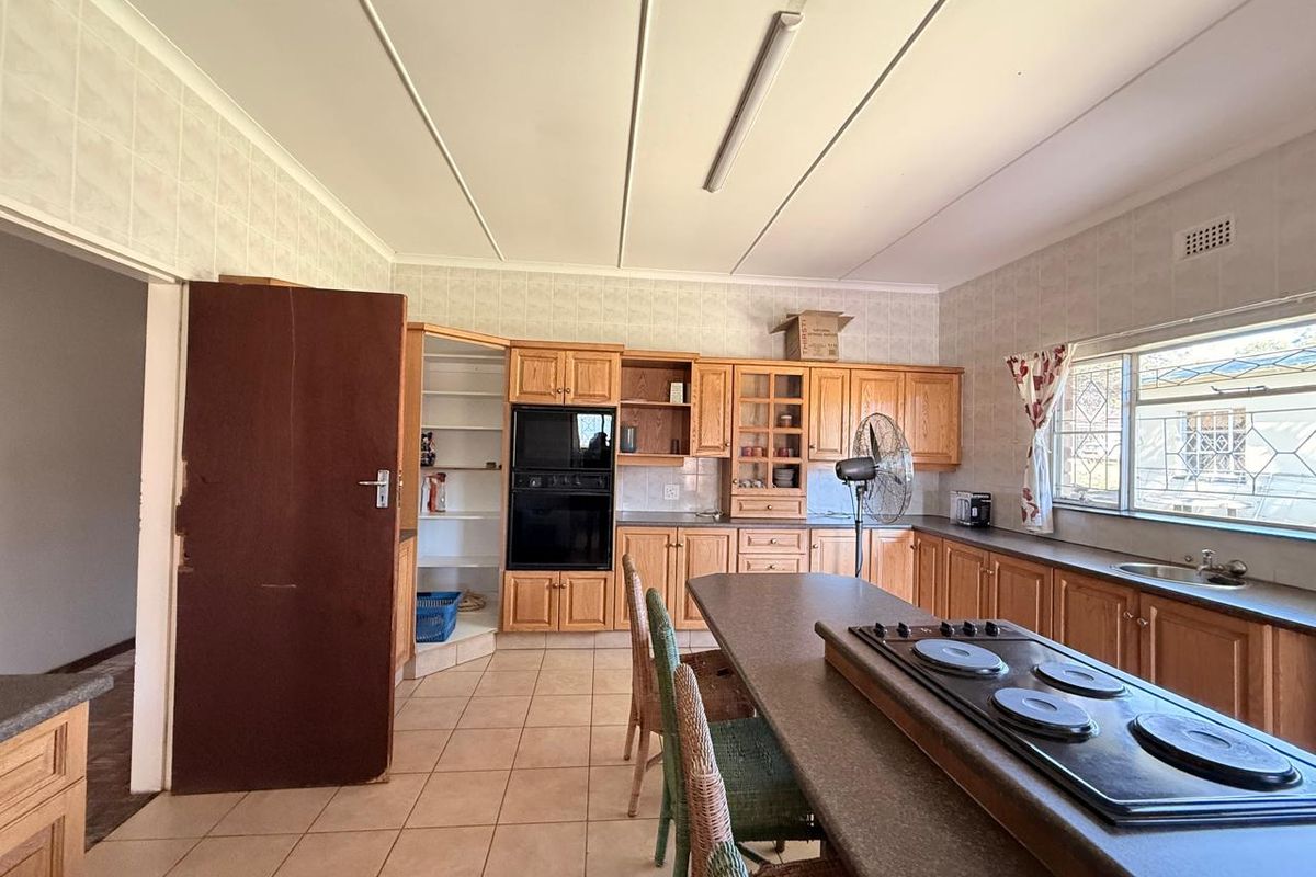 A spacious kitchen featuring wooden cabinetry, a built-in oven, and a central island with a cooktop, offering ample storage and prep space.