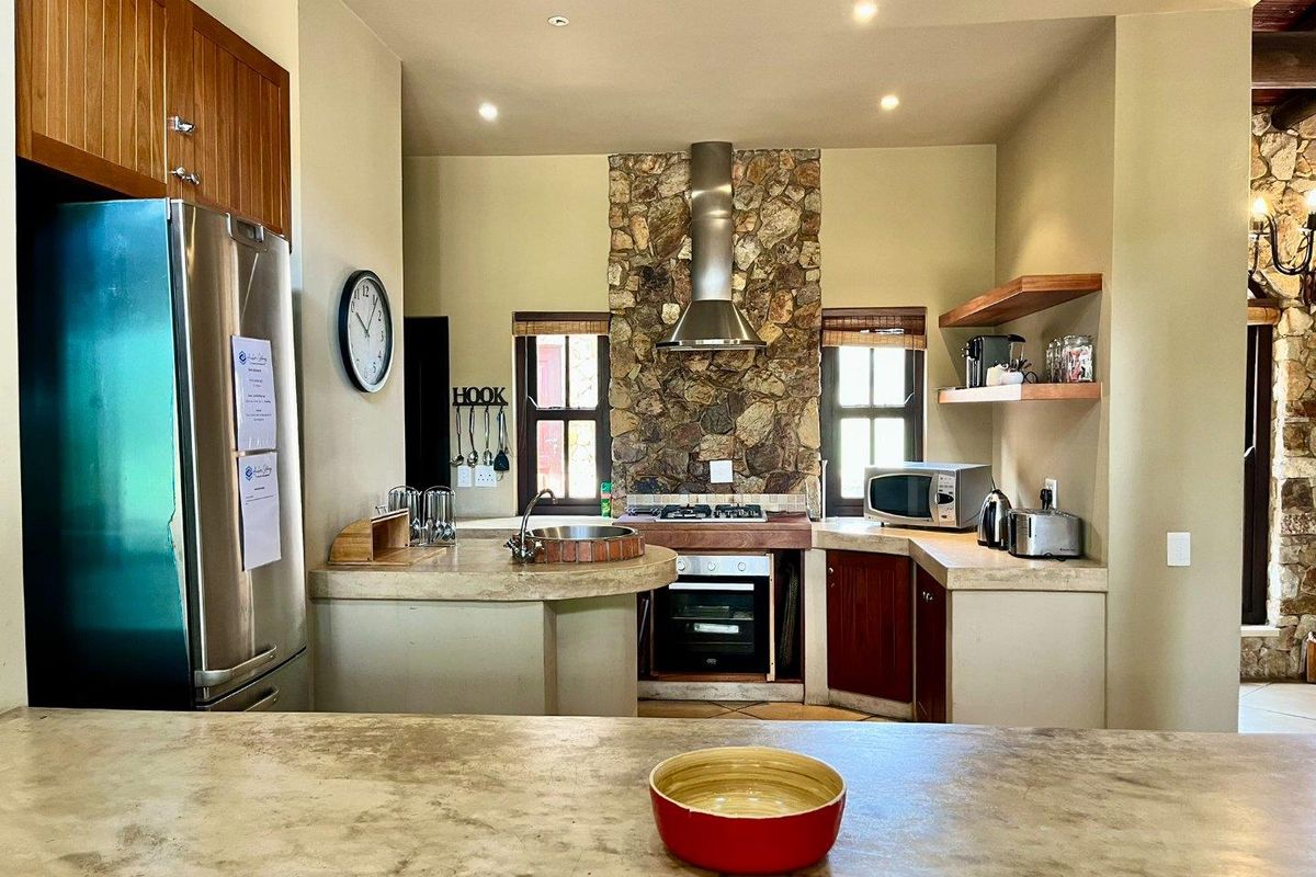 A rustic-style kitchen featuring stone cladding, wooden cabinetry, a built-in oven with extractor fan, and stone-topped counters.