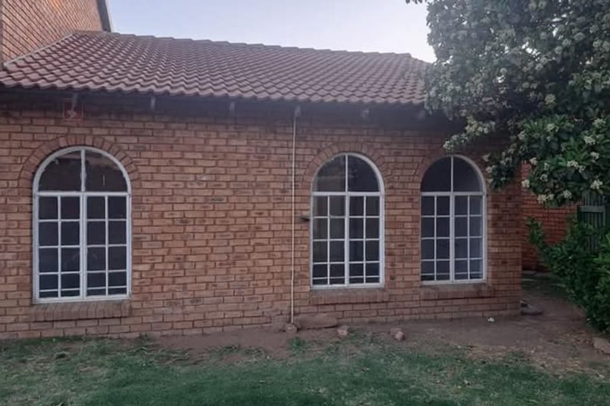 Rear exterior view of a face brick house featuring arched windows and a tiled roof.