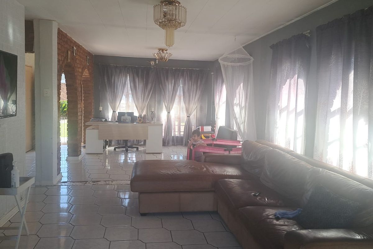 Spacious living area featuring exposed brick archways and tiled flooring, offering a versatile layout with natural light.