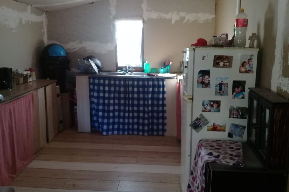 A rustic kitchen area featuring a sink, wooden flooring, and unfinished wall surfaces, offering significant potential for renovation and modernization.