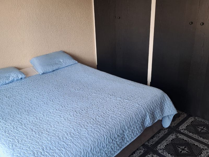 A bedroom featuring built-in cupboards and patterned floor covering, offering a functional space ready for cosmetic updates.