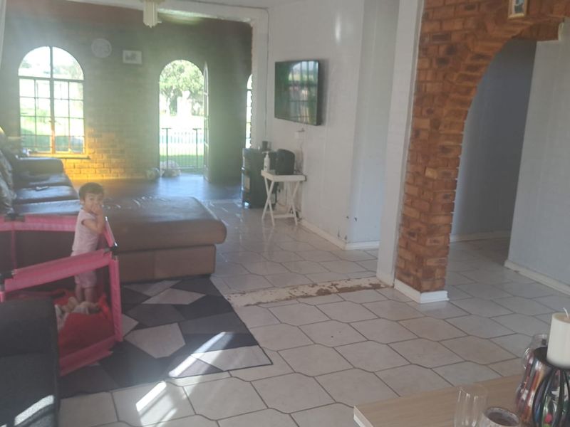 Spacious living area featuring distinctive exposed brick archways, tiled flooring, and arched windows providing natural light and access to the outdoor area.