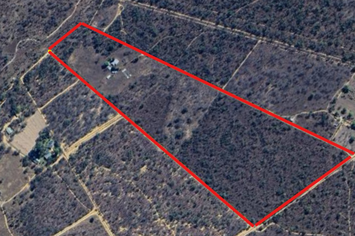 Aerial view of a large rural farm property with boundary lines highlighted, showing the expansive natural landscape and existing building footprint.