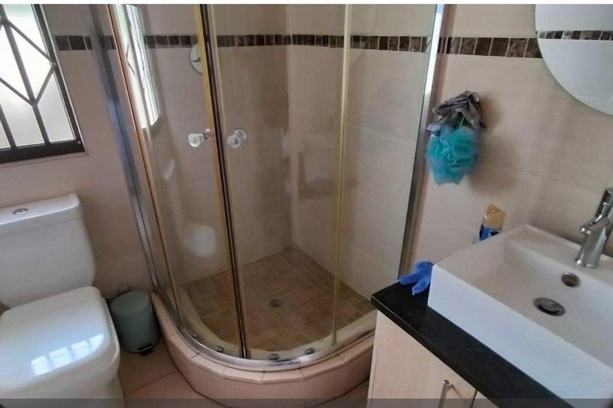 A functional bathroom featuring a corner shower enclosure, a modern vessel sink with vanity, and a standard toilet.