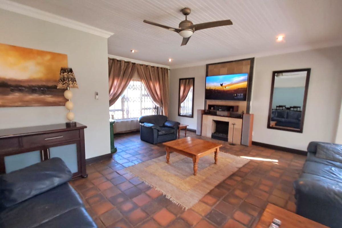 Spacious living room featuring a central fireplace, tiled flooring, ceiling fan, and recessed lighting, offering a comfortable and functional layout.